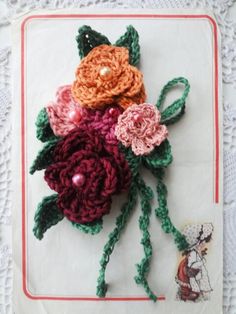 crocheted flowers are sitting on top of a piece of paper with pearls in the middle