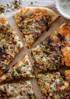 sliced pizza sitting on top of a cutting board next to a bowl of cheese and seasoning