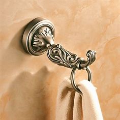 a towel hanging on the side of a wall next to a toilet paper holder with an ornate design