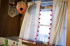 the kitchen window is decorated with red, white and blue polka dot curtains hanging from hooks