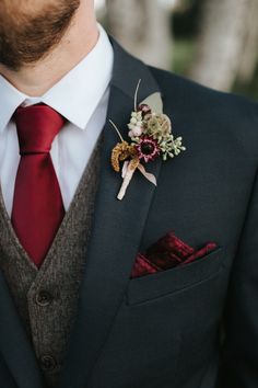 a man in a suit with a red tie and boutonniere