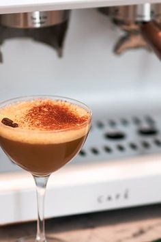 a drink sitting on top of a counter next to a stovetop oven with an espresso machine in the background