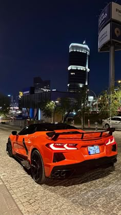 an orange sports car parked in front of a parking meter