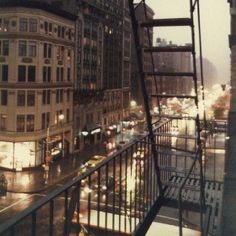 a city street filled with lots of traffic next to tall buildings in the rain at night