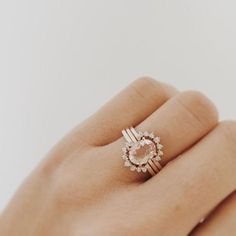 a woman's hand with a ring on top of her finger and an engagement ring in the middle