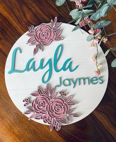 a sign that says layla james on it with flowers and leaves around the sign