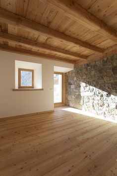 an empty room with wood flooring and stone wall in the corner, looking out to the outside