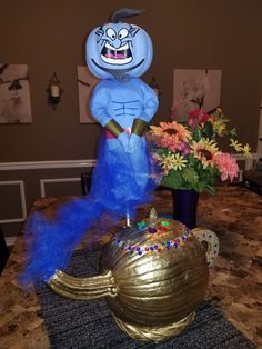 a blue and gold teapot sitting on top of a table next to a vase filled with flowers