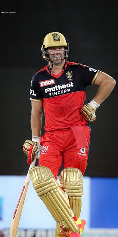 a man in red and black uniform holding a cricket bat