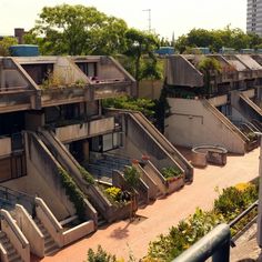 an apartment complex with stairs leading up to the top floors and plants growing on them