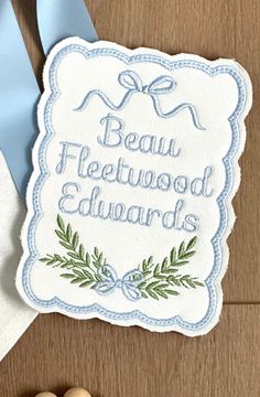 a blue ribbon and some buttons on a wooden table with a sign that says beau fleetwood awards