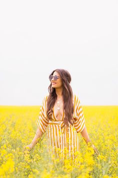 a woman standing in a field of yellow flowers