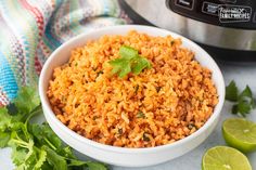 mexican rice in a white bowl with cilantro and limes next to an instant pressure cooker