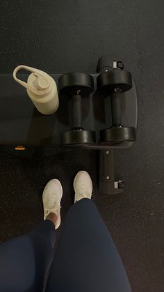 a person standing on a black surface with their feet propped up next to some cups