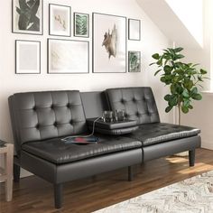 a black leather couch sitting in front of a white wall with pictures on the wall