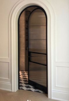 an arched glass door in the middle of a room with black and white checkered flooring