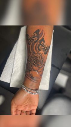 a woman's arm with a rose and butterflies tattoo on the left side of her arm