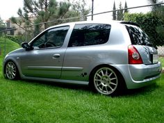 a silver car parked on top of a lush green grass covered field next to a fence