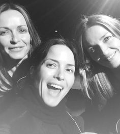 black and white photograph of three women smiling at the camera with their arms around each other