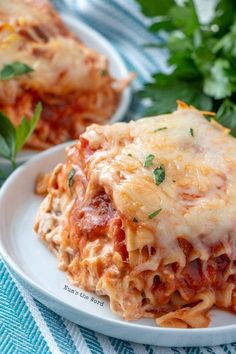 two white plates topped with lasagna covered in sauce and cheese, garnished with parsley