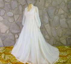 a white wedding dress is on display in front of a stone wall and yellow fabric