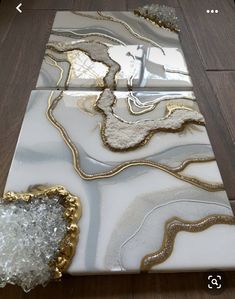 a white and gold marble table top on a wooden floor next to a glass vase