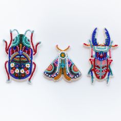 three beaded insect brooches sitting on top of each other next to each other