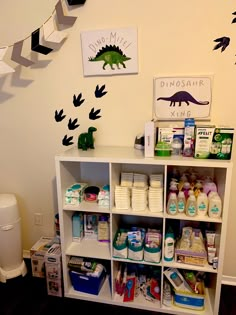 a baby's room with dinosaur wall decals on the walls and shelves full of diapers