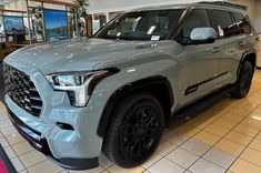 a silver suv parked in a showroom with tile flooring and large glass windows