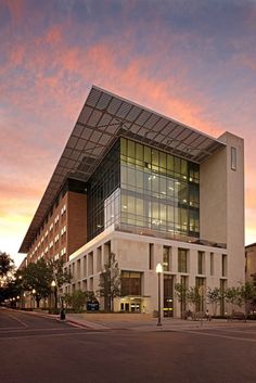 a large building with many windows and lights on it's sides at sunset or dawn