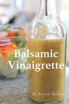 a bottle filled with dressing sitting on top of a counter next to a salad bowl