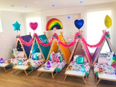 a group of children's teepees with rainbow decorations and balloons on them