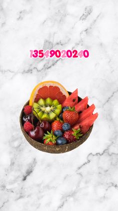 a bowl filled with fruit sitting on top of a white marble counter next to a pink sign