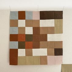 a piece of cloth hanging on a wall with different colored squares and rectangles