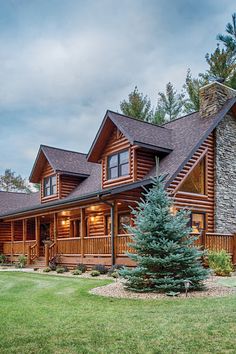 a large log home with a stone chimney and wraparound porches on the front lawn