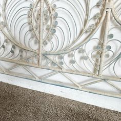 a close up view of a white metal headboard with decorative designs on the sides