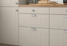 a kitchen with white cabinets and wooden counter tops