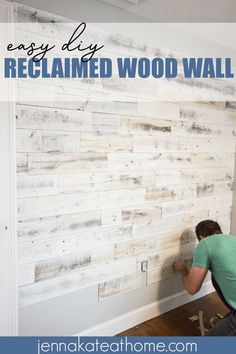 a man is painting a wooden wall with white paint and wood planks on it