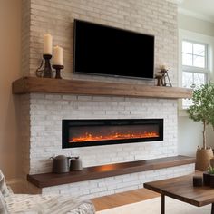 a living room with a fireplace and television mounted on the wall above it, along with candles