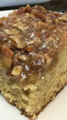 a piece of cake sitting on top of a white plate covered in icing and nuts