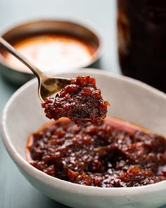 a spoon full of chili sauce in a white bowl