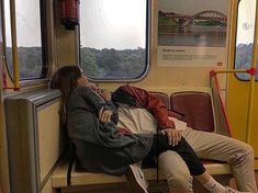 two people are sleeping on a train next to each other and looking out the window