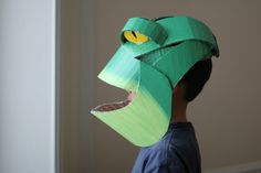 a young boy wearing a paper hat with an animal's head cut out to look like a snake