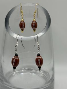 Show some team spirit with these football earrings! An acrylic football paired with metal and gemstone beads in various color combinations. Don't see one in your team colors? Message us and we'll be happy to make one.  As each piece is handmade, there may be slight variations in each.  Listing includes hypoallergenic ear wires; however, if you prefer .925 Sterling Silver or Gold Filled ear wires, please message us for a custom order.  Caring for your jewelry means you will enjoy its beauty for a Football Earrings, Vendor Events, Beads Charms, Sports Teams, Etsy Earrings Dangle, Color Calibration, How To Apply Makeup, School Spirit, Team Spirit