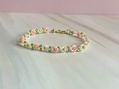 a bracelet with pink and green flowers on it