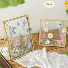 two small mirrors with flowers on them sitting on a table next to a lace doily