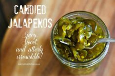 a jar filled with pickles sitting on top of a wooden table next to a spoon