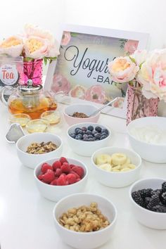 a table topped with bowls filled with different types of fruit and nuts next to a sign that says yogurt bar