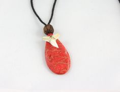 a red necklace with a white flower and a wooden bead hanging from it's side