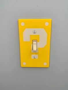 a yellow and white light switch sitting on top of a wall